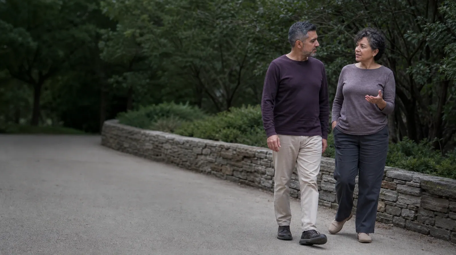Two adults walk and talk beside a garden wall · Adult Recovery Support Resources for Atlantis, FL Residents