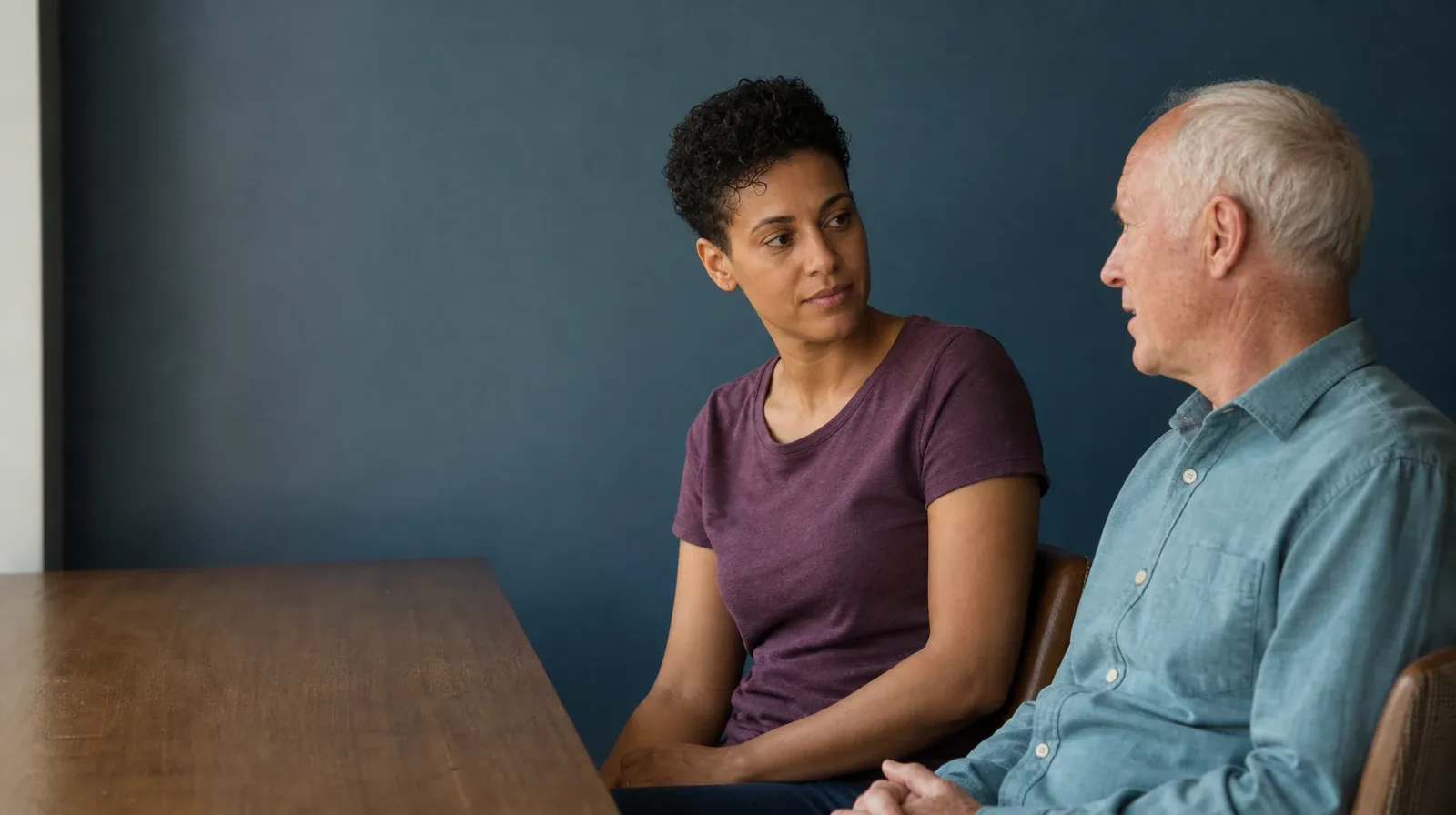 Addiction Treatment for Aventura, FL Residents | An adult turns from an empty desk toward another adult seated diagonally… An adult turns from an empty desk toward another adult seated diagonally… · Addiction Treatment for Aventura, FL Residents