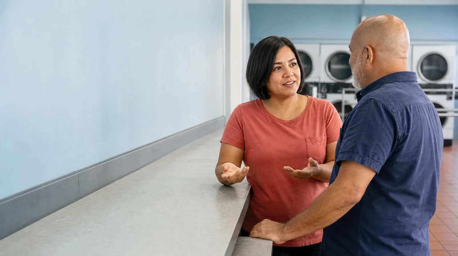 Two adults pause for an attentive conversation beside an unused laundry… · Addiction Treatment for Lauderhill, FL Residents