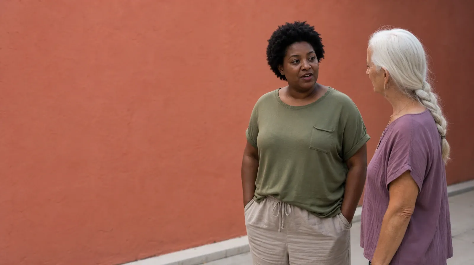Two adults talk beside a plain coral wall, with one keeping both hands in… · Addiction Treatment for Margate, FL Residents
