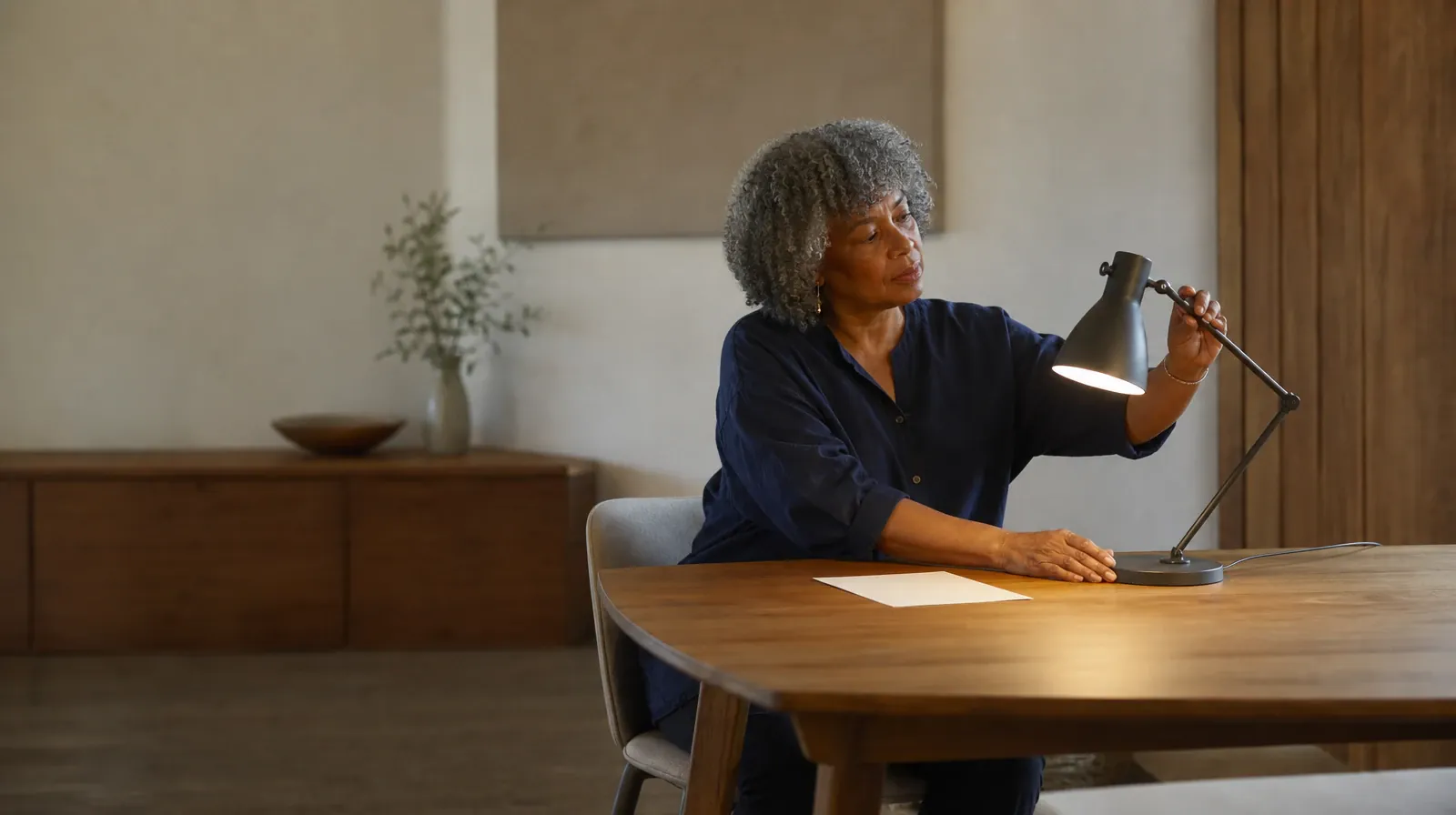 An adult adjusts a desk lamp beside blank paper · Treatment Cost Questions for Little Haiti, Miami, FL Residents
