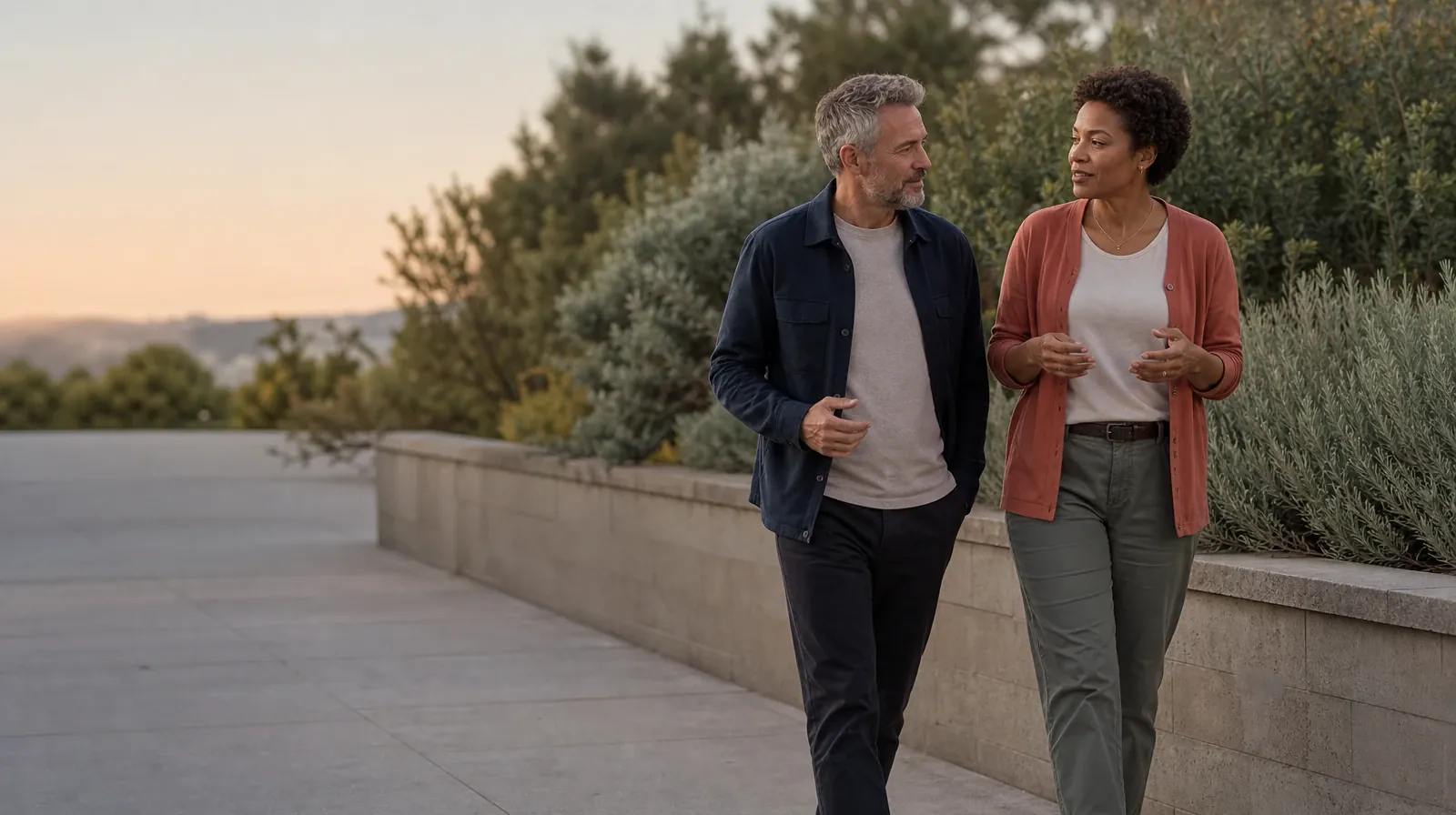 Two adults walk and talk beside a garden wall · Planning Time Away for Treatment for Pompano Beach, FL Residents