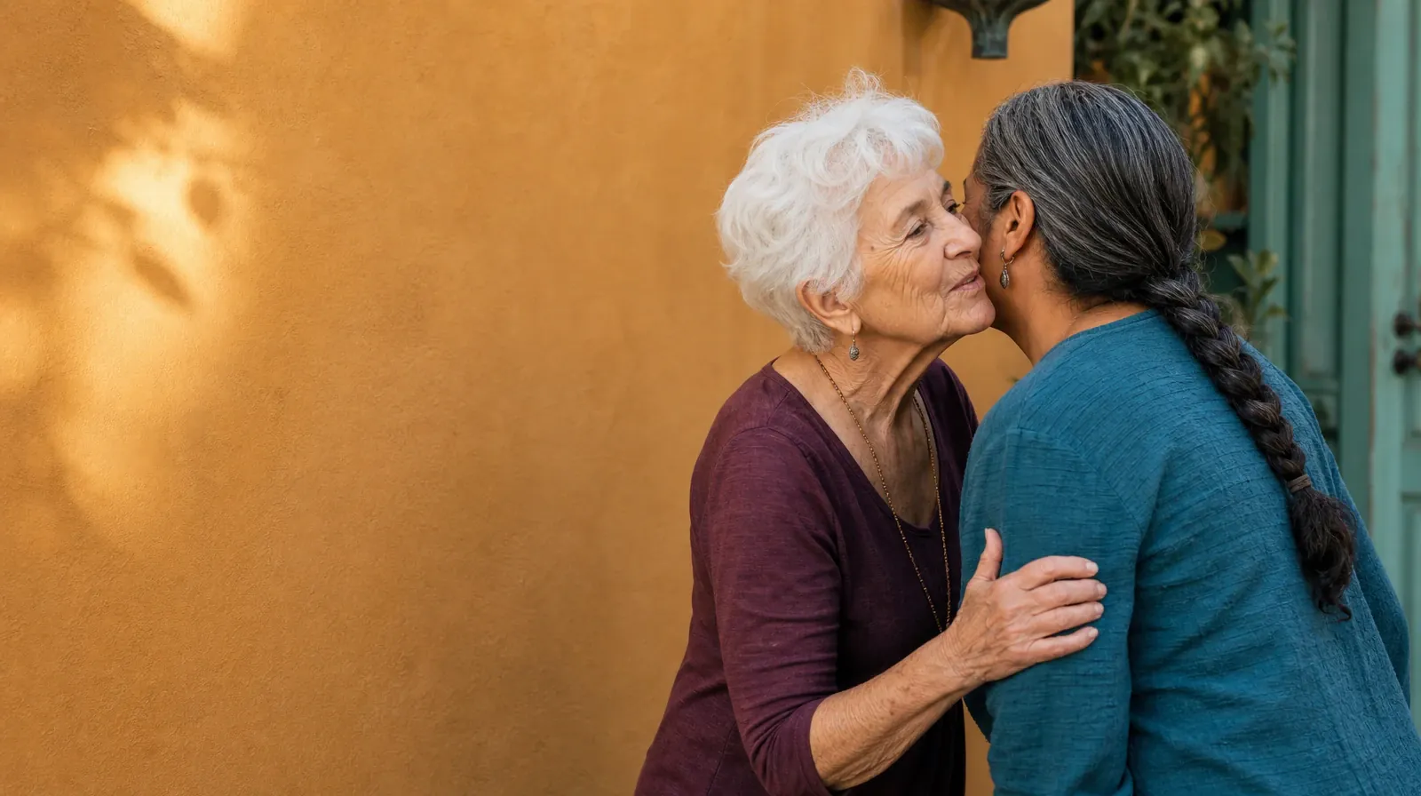Two adults share a brief cheek-to-cheek greeting beside an ochre wall · Cannabis Addiction Treatment in Miramar, FL