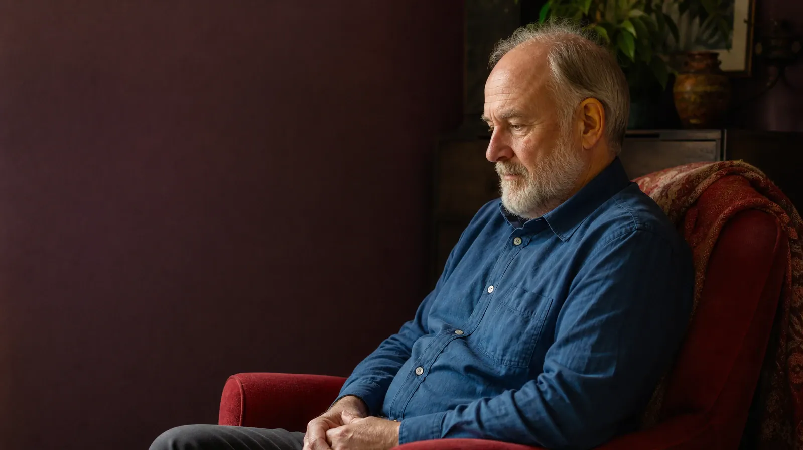 An adult sits in profile in a red armchair with hands resting loosely… · Privacy and Consent in Cognitive Behavioral Therapy