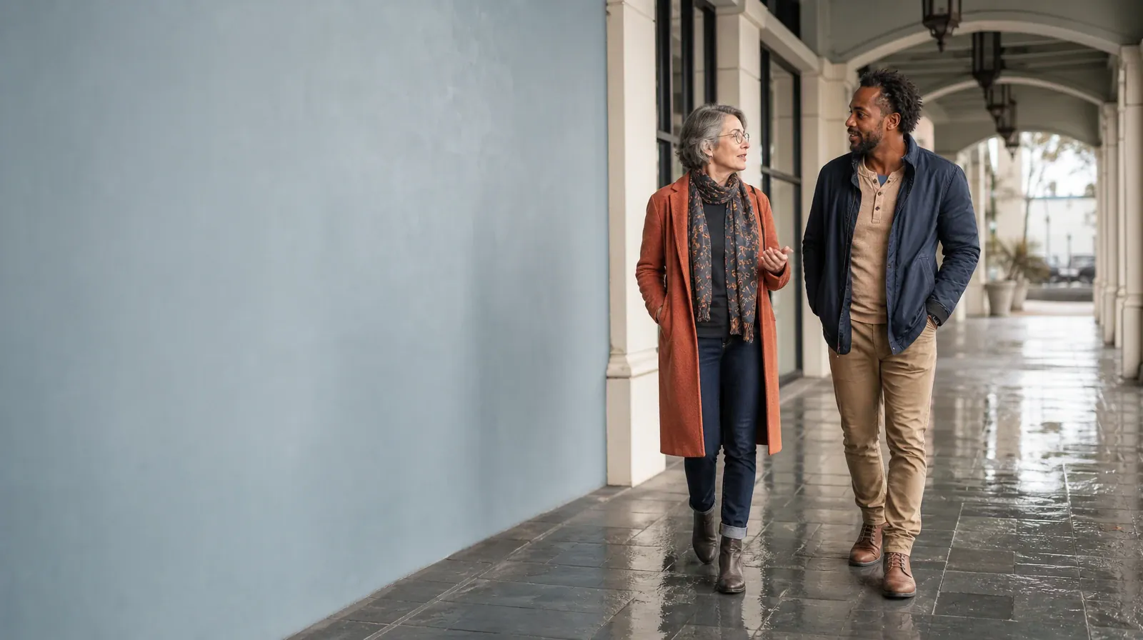 Two adults walk and talk beneath a covered arcade · Mindfulness After Residential Care